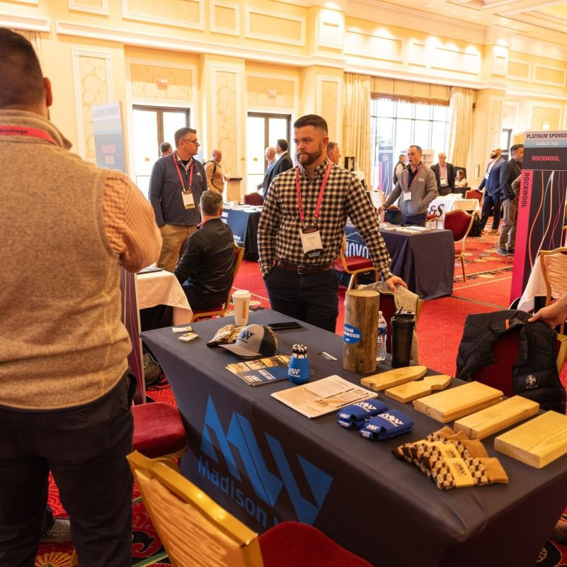 Vendor booth displaying wood samples and promotional items at an industry event